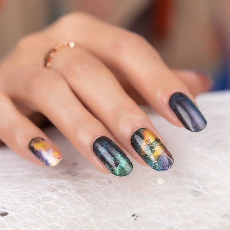 Hand wearing marble nail wraps in green gold and navy blue stone effect design