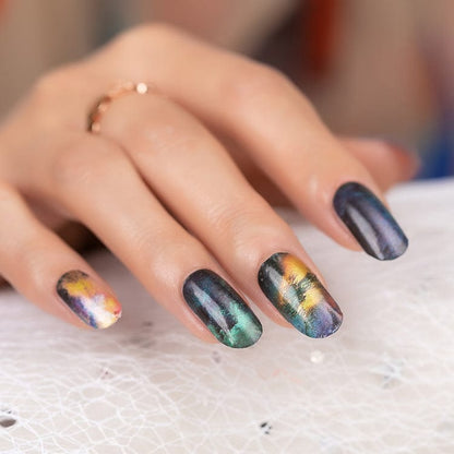 Hand wearing marble nail wraps in green gold and navy blue stone effect design