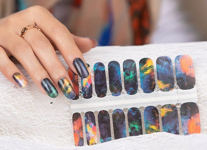 Hand displaying dark marble nail wraps with orange and green volcanic swirl patterns