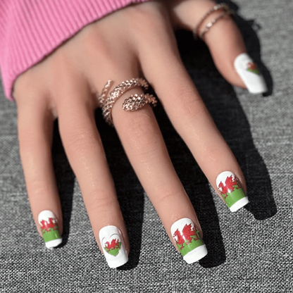 Hand wearing pink jumper showing Welsh dragon nail art wraps with red green patriotic design