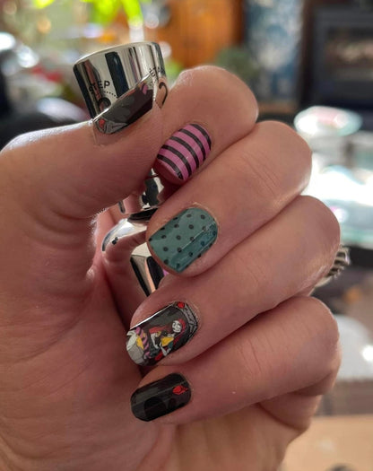 Gothic nail art wraps on hand with black, teal polka dot, pink stripe character designs