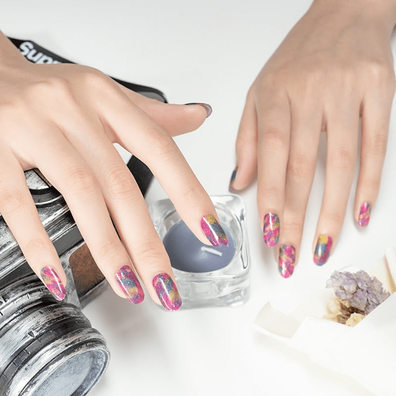 Two hands showcasing bright multicoloured brushstroke nail wraps with rainbow abstract paint effect nail art