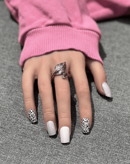 Hand wearing mauve and leopard print nail wraps showing mixed animal print manicure style