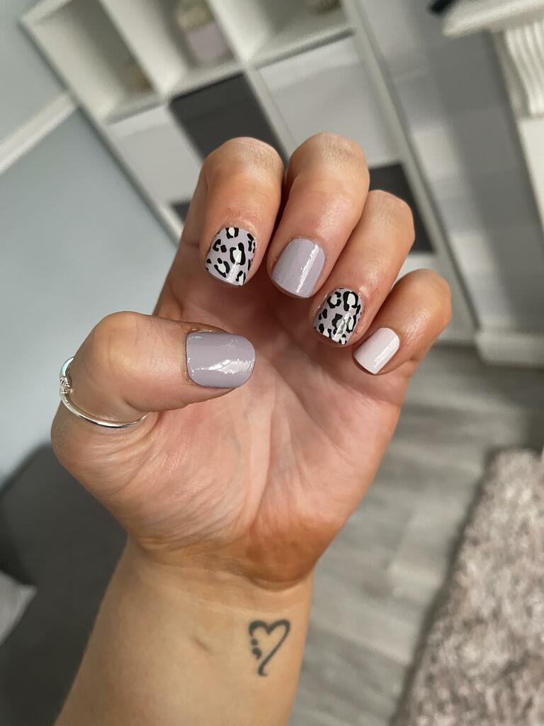 Hand displaying mauve and black leopard print nail wraps for trendy animal print manicure