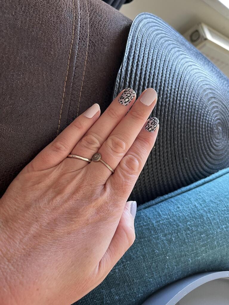 Hand wearing black and mauve leopard print nail wraps in animal print design
