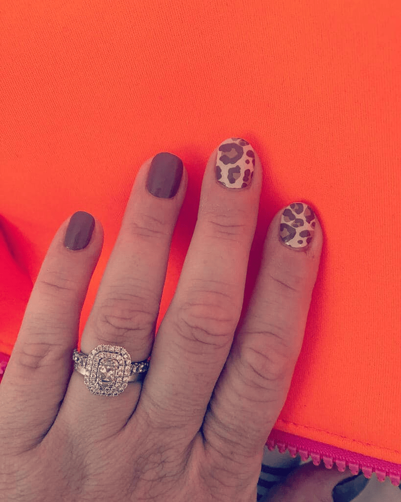 Hand wearing leopard print nail wraps in plum and neutral tones for autumn manicure
