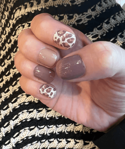 Autumn leopard nail wraps on hand featuring brown taupe animal print design for cosy manicure
