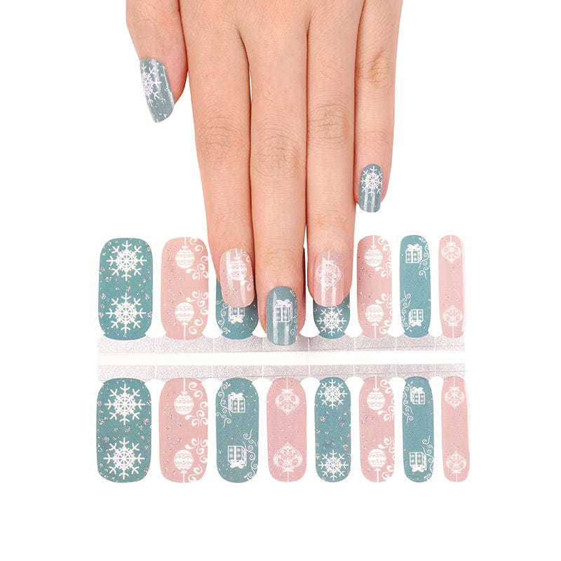 Hand wearing festive Christmas nail wraps with pink and sage green snowflake patterns