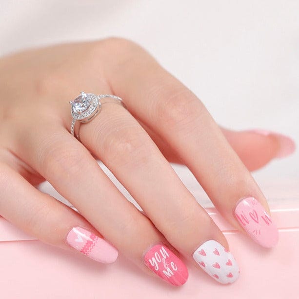Pink and white heart pattern nail wraps with romantic script text on hand