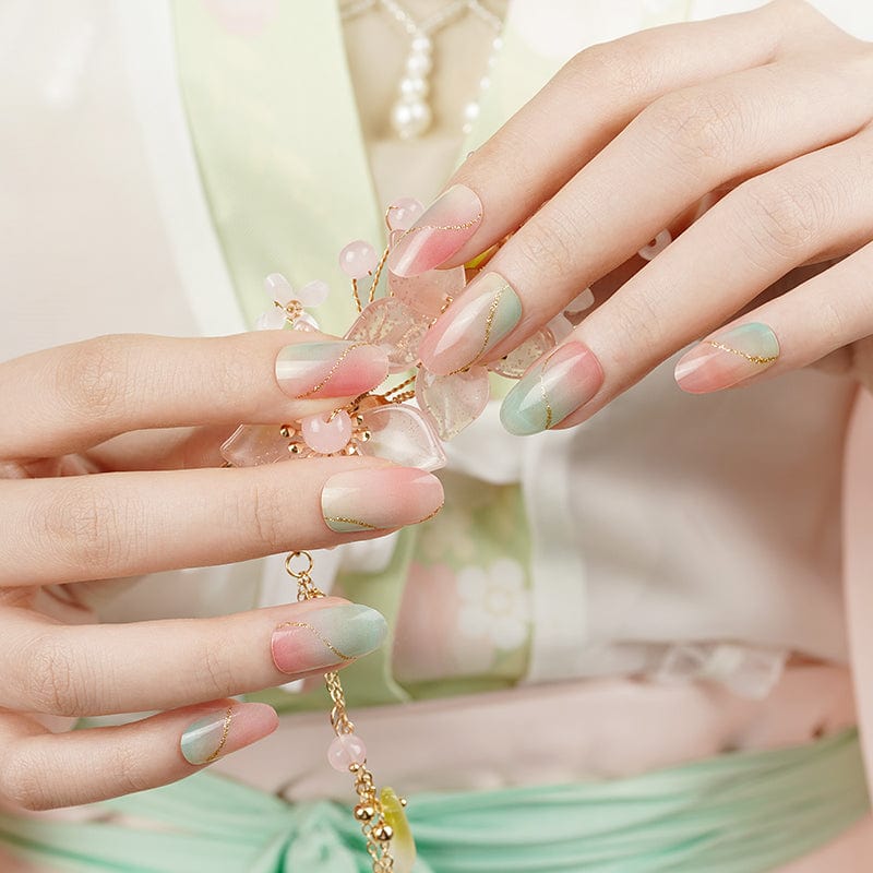 Two hands showing pink and green marble nail wraps with gold jewellery accessories