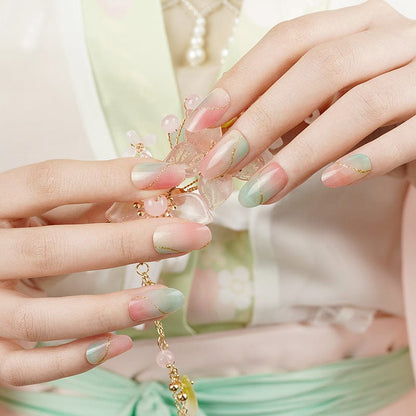 Two hands showing pink and green marble nail wraps with gold jewellery accessories