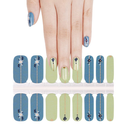 Hand wearing blue and sage green nail wraps with folk art daisy and leaf patterns