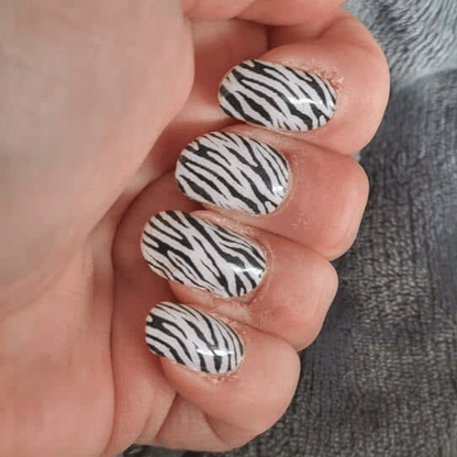 Zebra stripe nail wraps displayed on hand featuring black and white animal print design