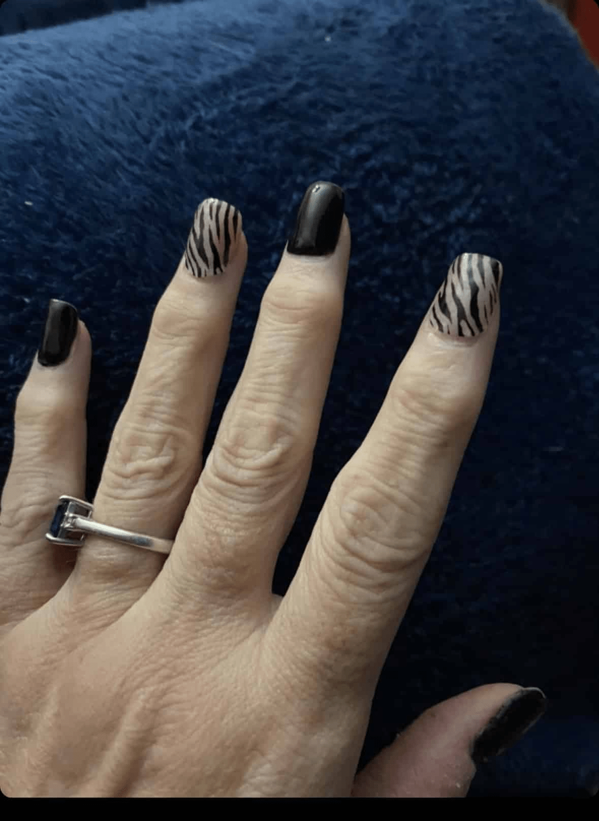 Zebra pattern nail wraps on hand showing black stripes on white base animal print