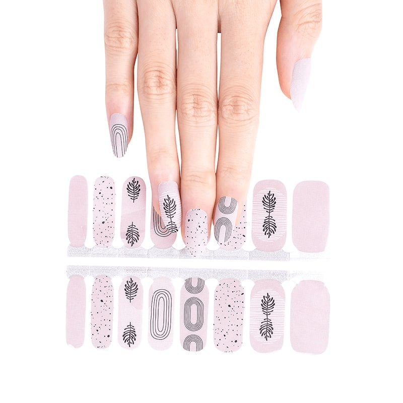 Hand with nail wrap sheet showing zen botanical patterns in black on nude pink base