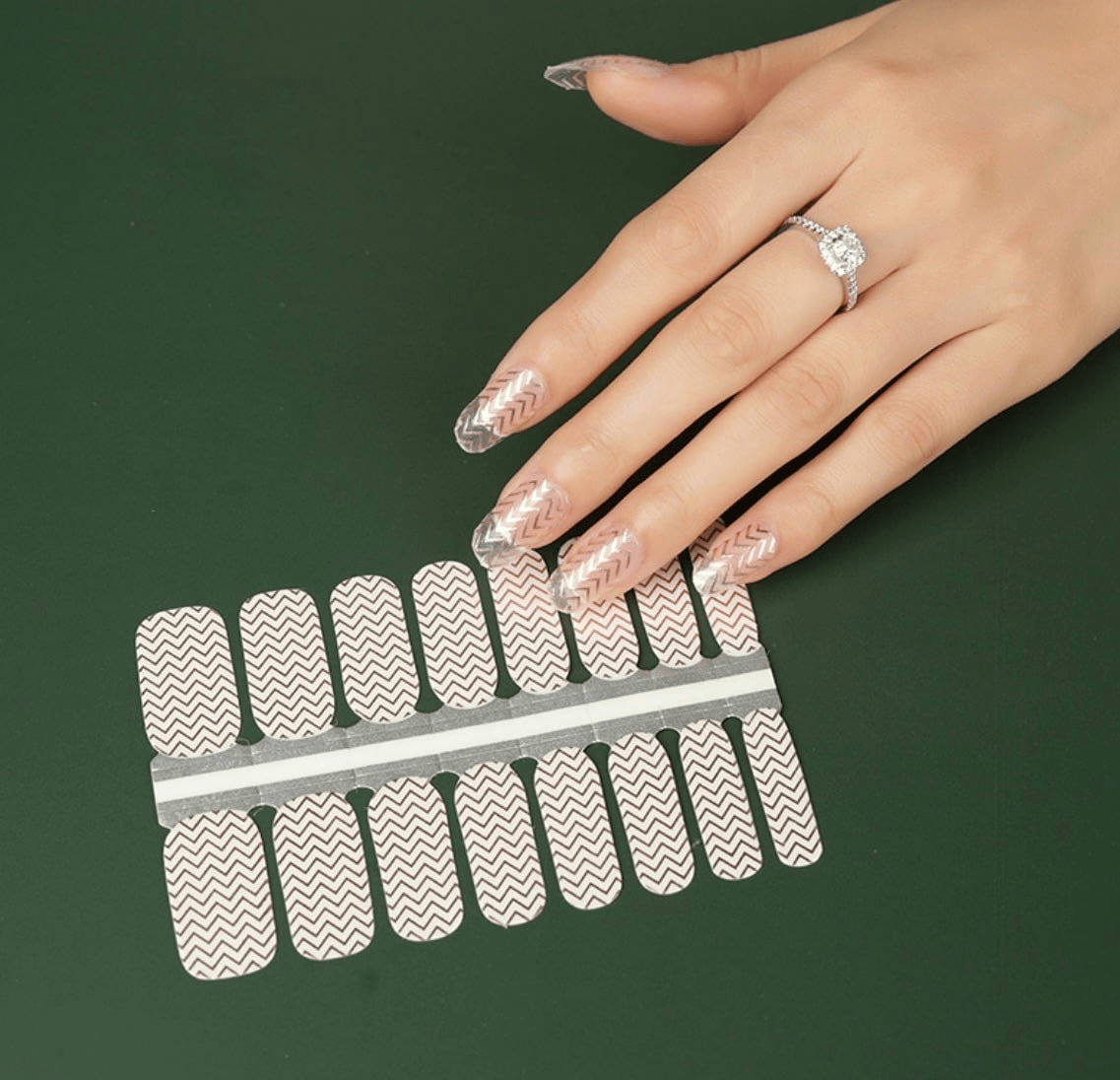Silver chevron nail wraps on hand with geometric zigzag pattern and clear base