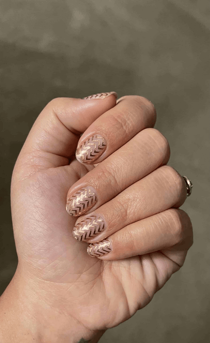 Hand wearing gold chevron geometric nail wraps with clear base and metallic zigzag pattern