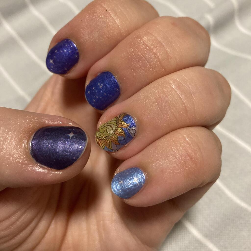 Blue celestial nail wraps with gold zodiac constellation designs on hand manicure