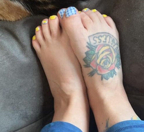 Blue and yellow gingham pedicure wraps on feet with checkered nail art design
