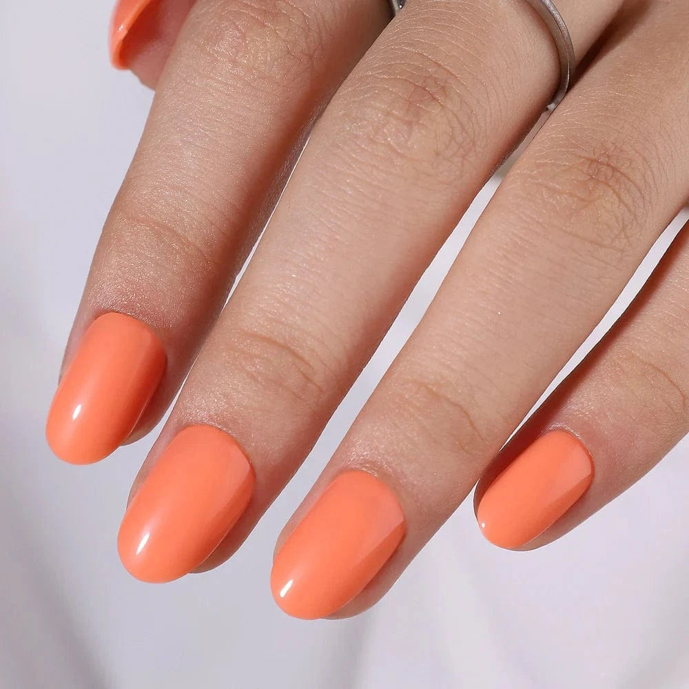Bright orange glossy press-on nails in short oval shape on hand