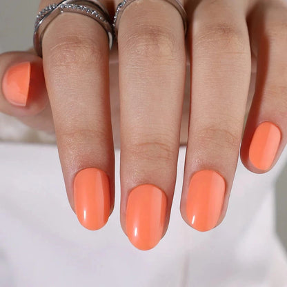 Vibrant orange glossy press-on nails oval shape summer manicure on hand