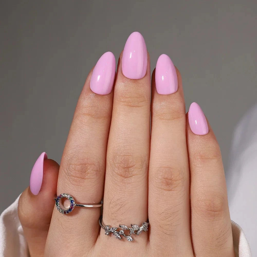 Short almond pink press-on nails glossy finish on hand with decorative silver rings