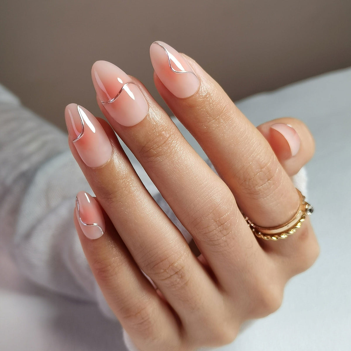 Glossy rose pink chrome press-on nails in short almond shape on hand