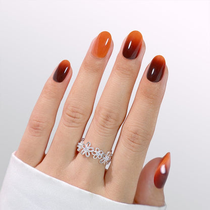 Orange ombre gel press-on nails in short oval shape on hand with silver ring