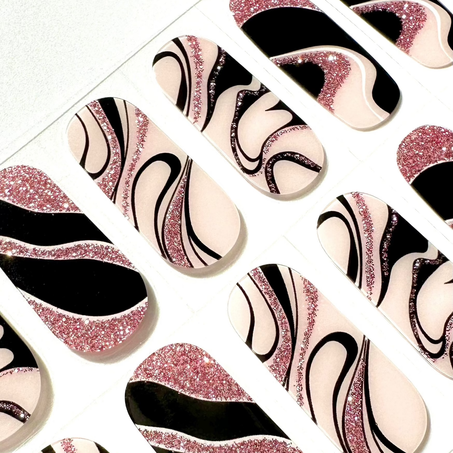 Close-up of pink glitter black marble gel nail wraps with artistic swirl patterns