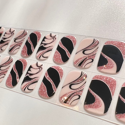Close-up of pink glitter and black marble effect gel nail wraps with swirl pattern