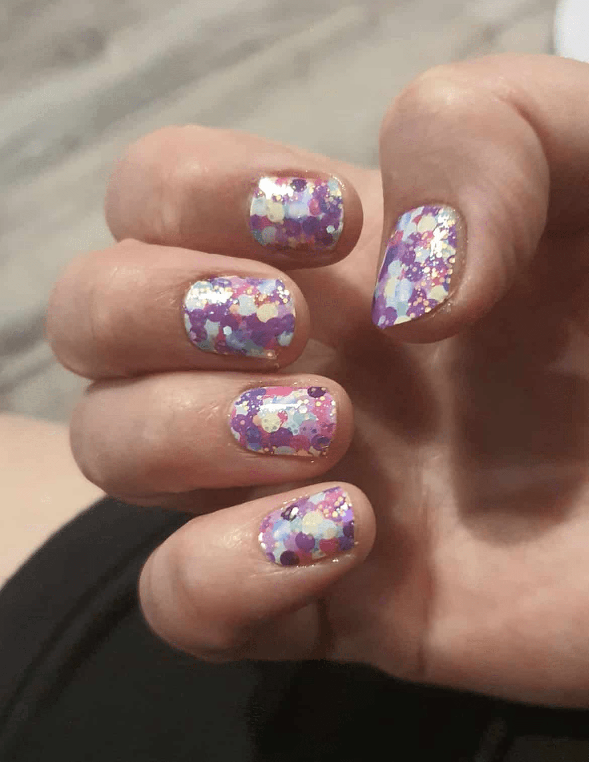 Purple glitter polka dot nail wraps on hand displaying sparkly multicoloured party nail art