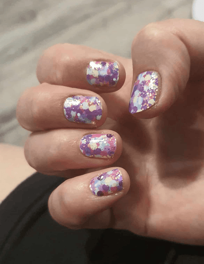 Purple glitter polka dot nail wraps on hand displaying sparkly multicoloured party nail art