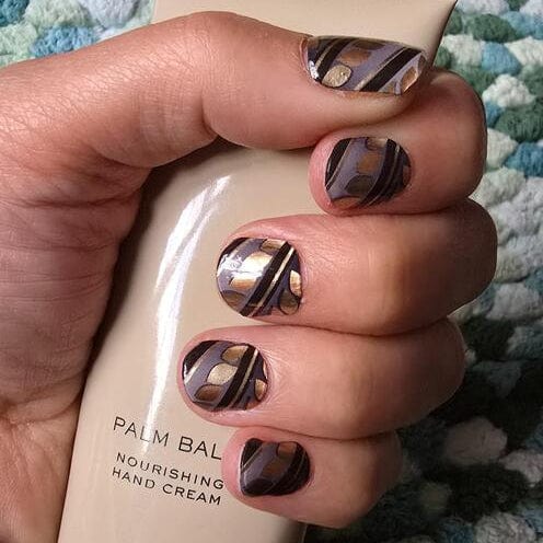 Hand holding cream showing brown marble stripe gel nail wraps at-home manicure