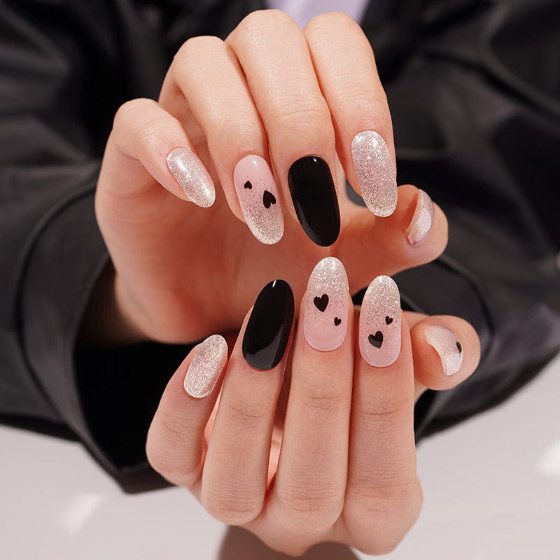 Two hands showing black heart gel nail wraps with pink glitter Valentine's Day nail art