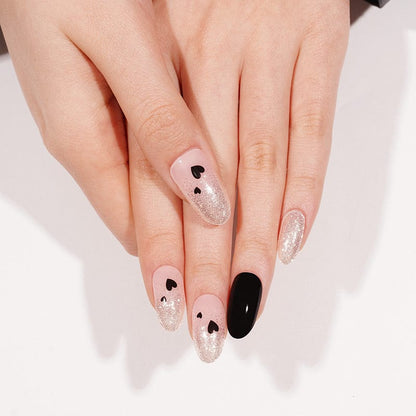 Pink glitter gel nail wraps with black heart nail art on hands
