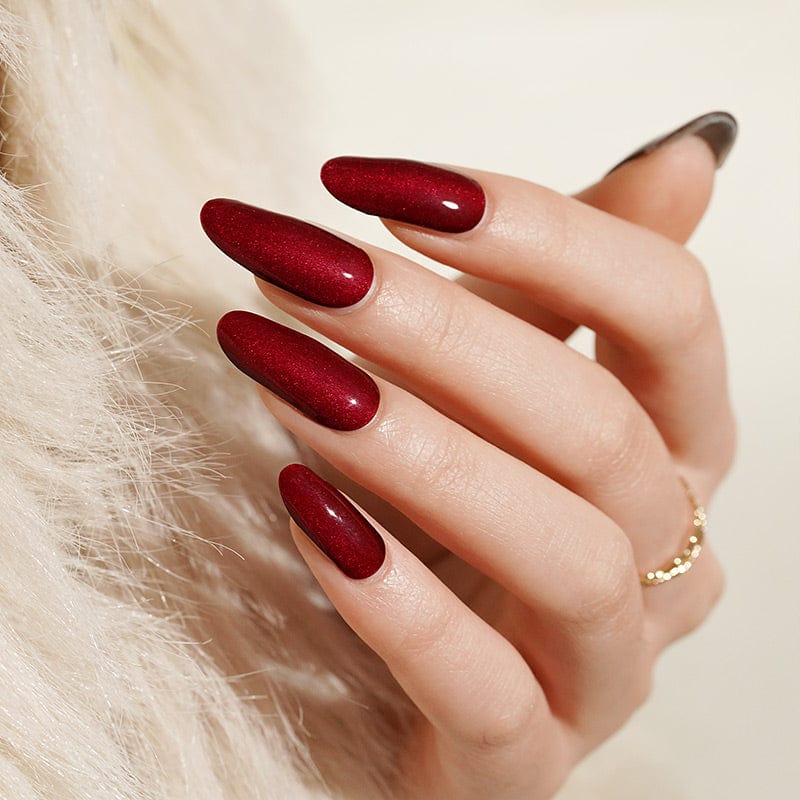 Deep red glossy gel nail wraps on hand showing almond shaped manicure