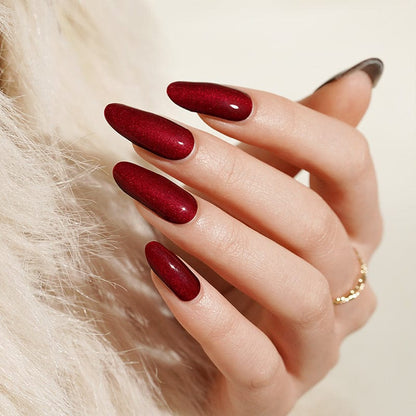 Deep red glossy gel nail wraps on hand showing almond shaped manicure