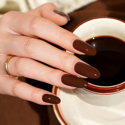 Deep chocolate brown gel nails on hand holding coffee cup showing glossy finish