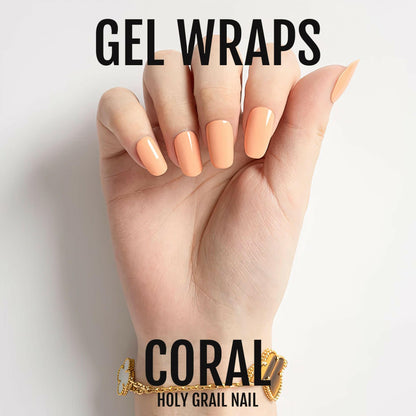 Hand wearing coral orange gel nail wraps with gold bracelet accessory