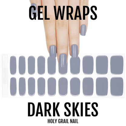 Hand showing dark grey gel nail wraps with nail art sheet displaying full set