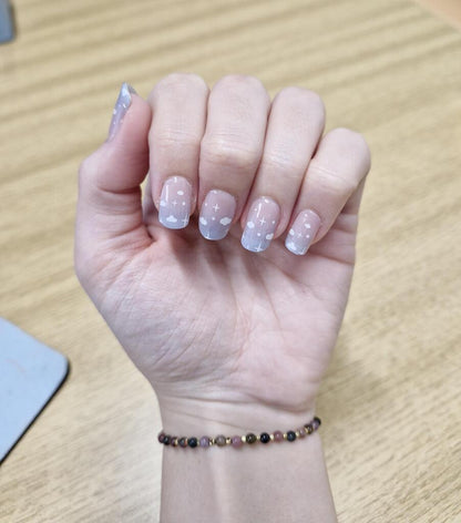 Blue cloud gel nail wraps on hand showing delicate sky pattern nail art