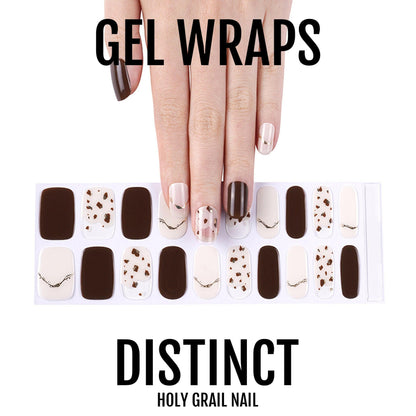 Hand wearing brown and nude gel wraps with gold polka dot nail art design