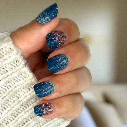 Hand wearing navy blue glitter gel nail wraps with rose gold sparkle accent nails