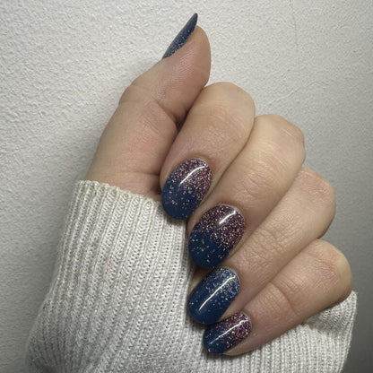 Close-up of navy blue to rose gold gradient glitter gel nail wraps on hand