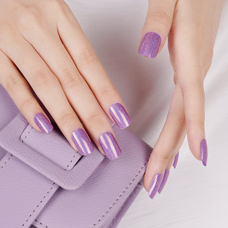 Purple holographic gel nail wraps on hand holding lilac handbag showing shimmer finish