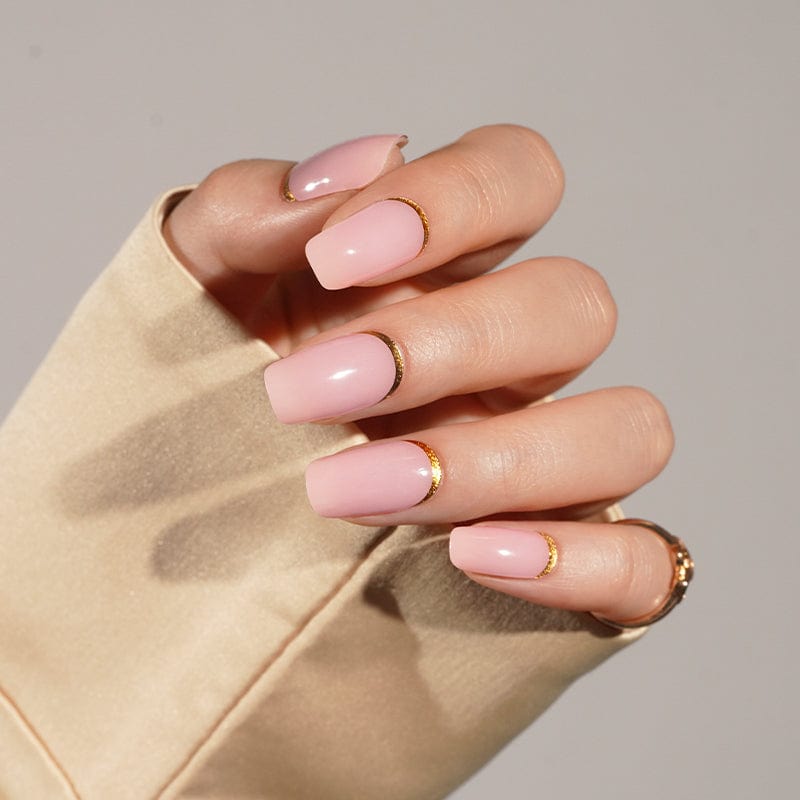 Hand gesture displaying pink gel nail wraps with subtle gold glitter finish