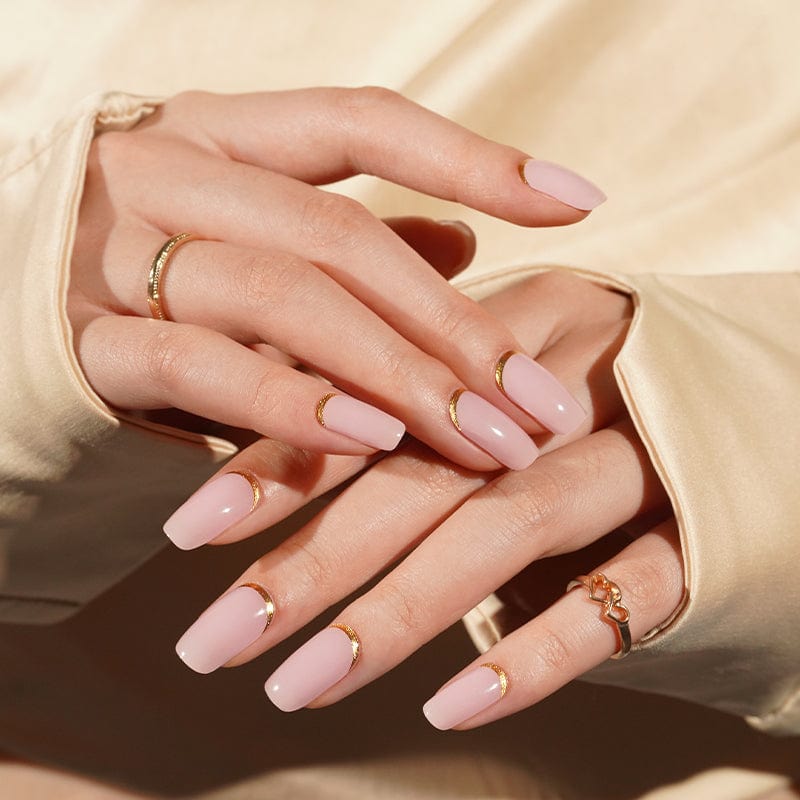 Two hands showing soft pink semi-cured gel nails with gold metallic shimmer