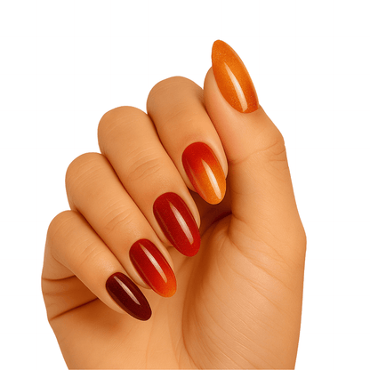 Hand wearing glossy amber gradient gel nails in warm orange to burgundy ombre finish