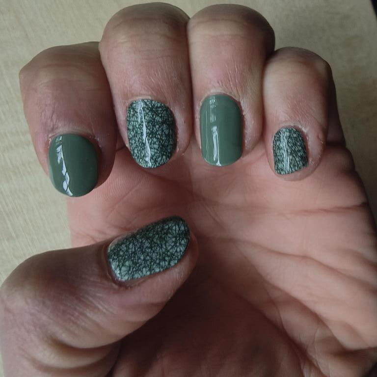 Close-up of forest green gel nails with sparkly glitter accent nails manicure