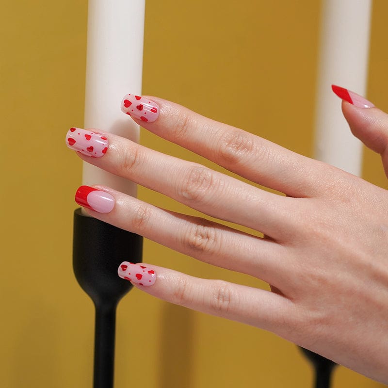 Valentine's gel nail wraps with red hearts and pink dots on hand manicure